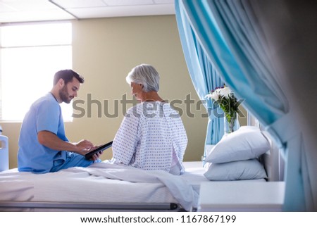 Male doctor showing medical report to female senior patient on a digital tablet in the hospital
