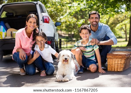 Happy family on a picnic sitting next to their car on a sunny day