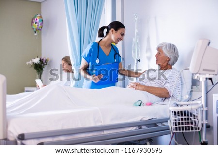 Female doctor interacting with female senior patient in the ward at hospital