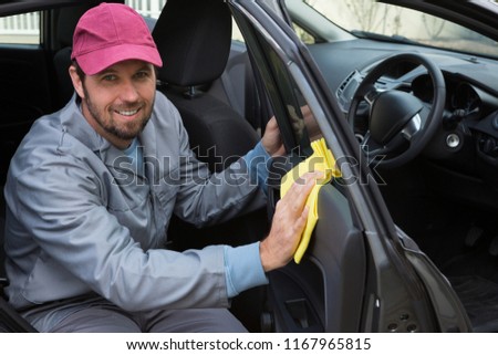 Portrait of smiling male auto service staff cleaning car door