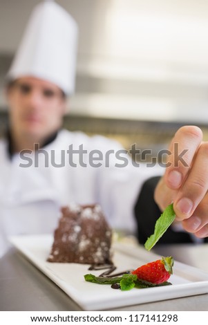 Mint leaf being put onto dessert plate of chocolate cake by chef