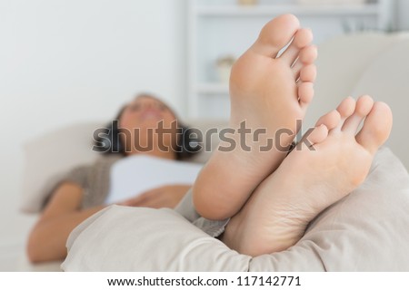 Woman with her feet up listening to music on the sofa