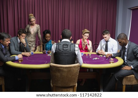 People sitting at the poker table playing cards in casino