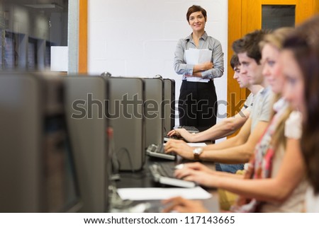 Teacher standing while students sitting at the computer room in college