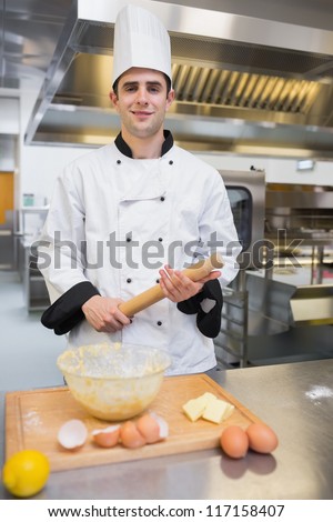 Pastry chef holding rolling pin while making dough in the kitchen