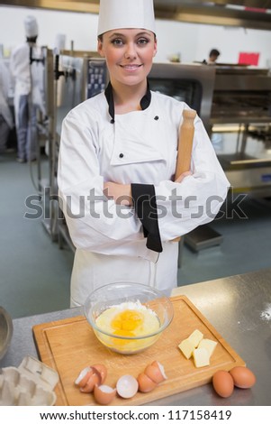 Smiling pastry chef with rolling pin making dough