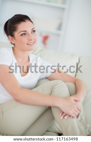Thinking woman sitting on the couch in the living room and smiling