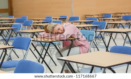 Woman leaning on desk napping in exam hall
