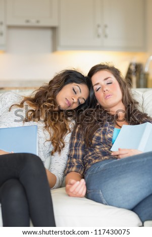 Two girls sleeping on couch taking break from studying on sofa