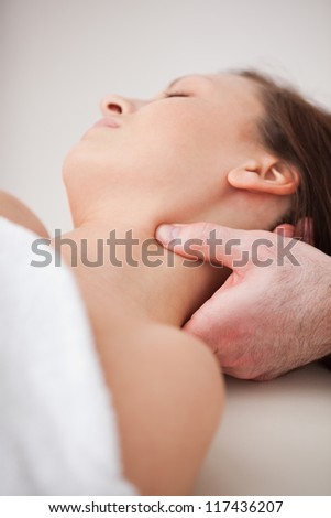 Close-up of doctor pressing his thumb on the neck of his patient indoors