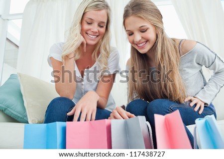 A pair of smiling girls looking into the clothes bags they have