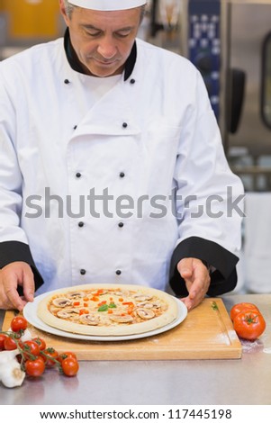Chef preparing a mushroom pizza in kitchen
