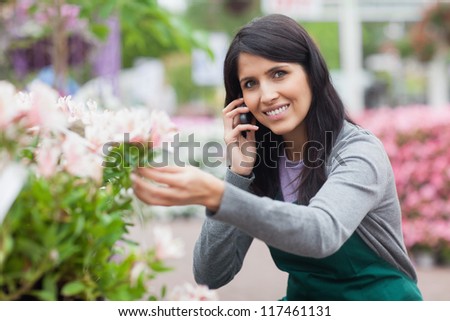 Florist touching a flower while calling in the garden centre