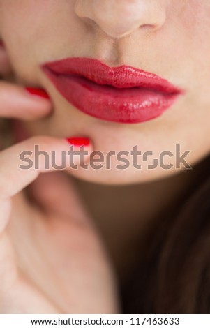 Close-up of woman showing her red lips while touching her chin