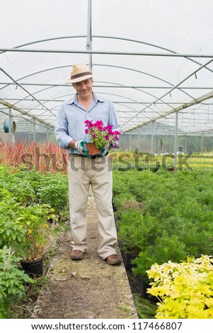 Smiling man holding a flower in greenhouse
