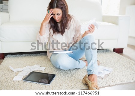 Woman with tablet pc calculating bills on the carpet