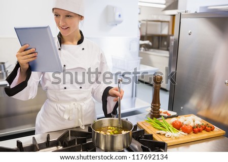 Female chef using tablet pc while cooking a soup