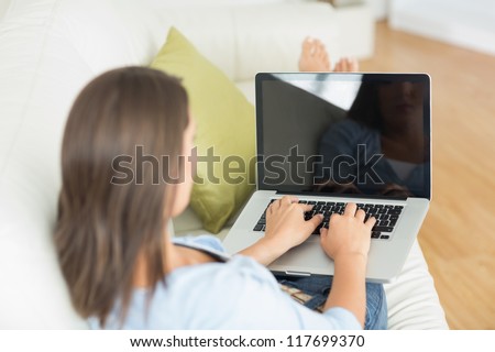 Rear view of woman using laptop on sofa in the living room