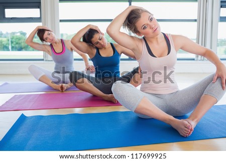Women stretching in bound angle yoga pose in fitness studio