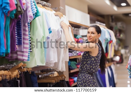 Woman sorting clothes on rail in clothes shop