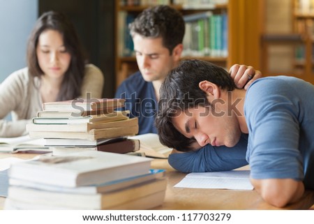 Student sleeping at study table in library