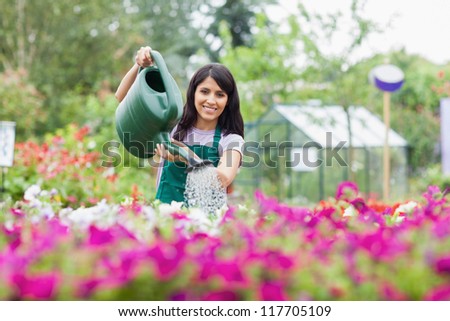 Cheerful gardener watering plants outside in garden center