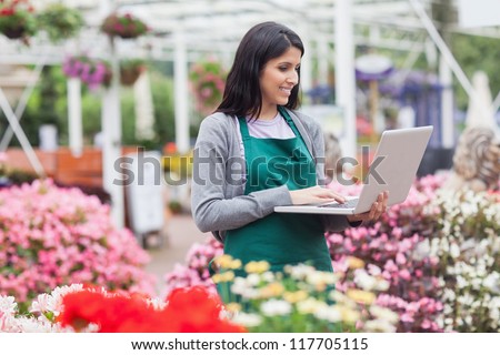 Woman doing stocktaking with laptop in garden centre