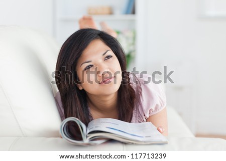 Woman lays on a sofa while reading a magazine in a living room