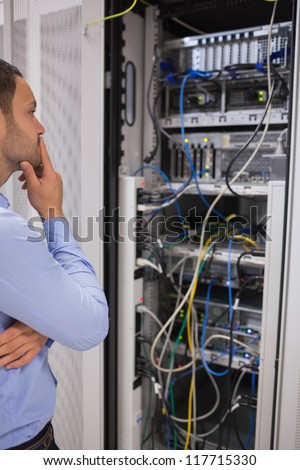 Thoughtful man looking at servers in data centre