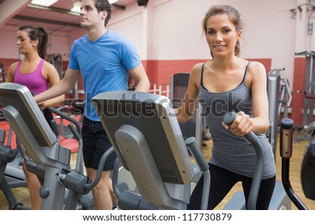 Three people stepping on step machine in gym