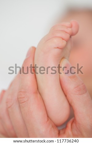 Fingers touching the foot of a baby against a grey background
