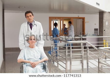 Old weak woman sitting on the wheelchair being pushed by doctor