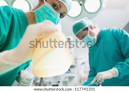 Close up of a nurse holding an anesthesia mask in an operating theatre