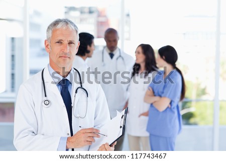 Mature doctor pointing seriously at something on his clipboard