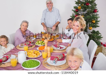 Happy family at christmas dinner with grandfather carving the turkey