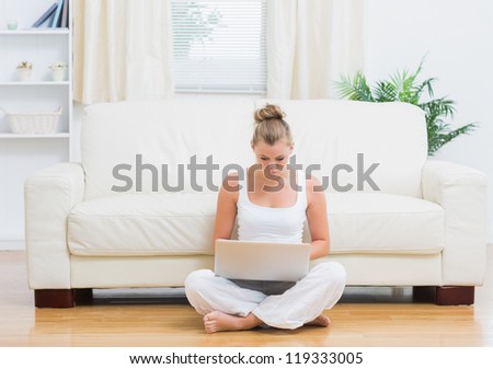 Blonde sitting on the floor while typing on laptop