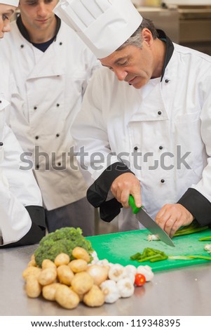 Chef teaching group how to slice vegetables in the kitchen