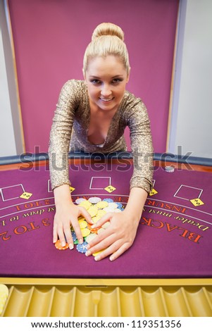 Woman standing at table in a casino and grabbing chips