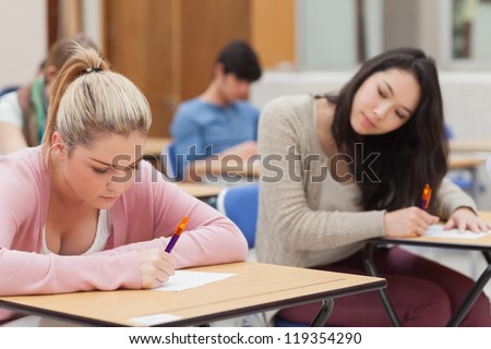 Burnette is trying to copy blonde student in exam in exam hall in college