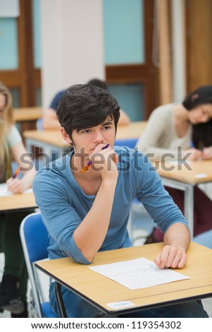 Student thinking during exam in exam hall in college