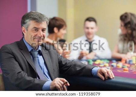 Man with cigar taking break from roulette table in casino