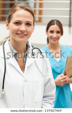 Doctor standing in a hospital reception with a nurse while smiling