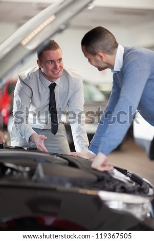 Two men looking at a car engine in a car shop