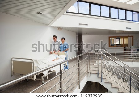 Doctor and nurse pushing patient in bed in the hallway