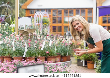Smiling florist looking at clay pots in garden center