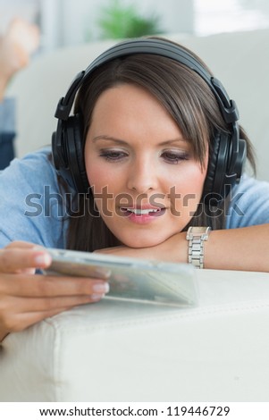 Woman listening music and looking at cd on sofa in the living room