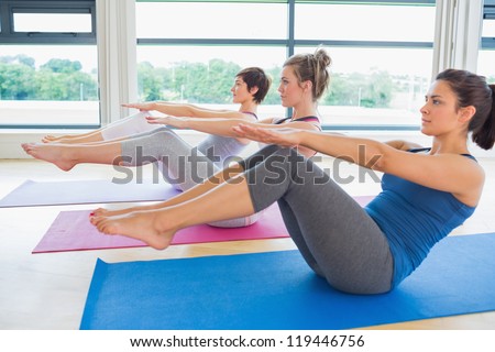 Women At Yoga Class In Boat Pose In Fitness Studio