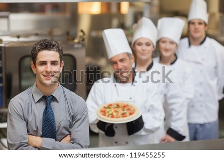 Waiter standing in front of Chef\'s holding a pizza