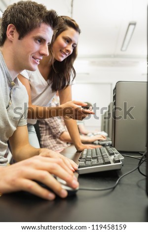 Students sitting at the computer at the computer room with woman pointing at screen