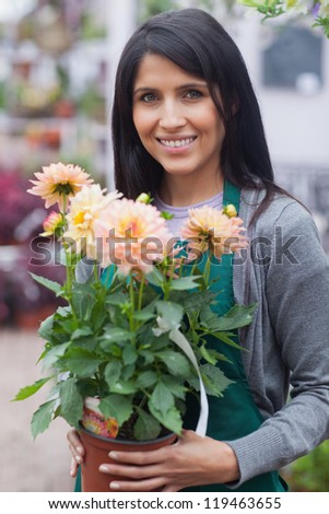 Employee smiling and holding a flower while standing outside in garden center